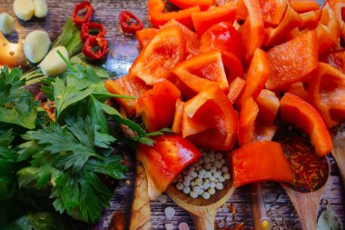 Kesme tahtasındaki sebzeler ve bitkiler. Dilimlenmiş domates, dolmalık biber, biber, sarımsak ve maydanoz. Yaz salatası malzemeleri. Sağlıklı beslenme. Organik gıda geçmişi.