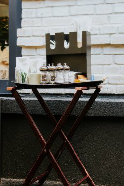 Biber, tuz ve peçeteyle hazırlanmış bir masa. Kaldırımdaki kafe mobilyaları. Restoranda yemek servisi. Biber, tuzluk ve menü masası. Mutfak aletleri. Açık hava restoranındaki mutfak eşyaları.. 