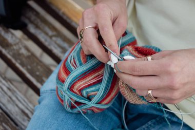 Parlak yün ve örgü iğneli kadın elleri. Örgü ören kız. Örgü örmek moda. Samimi bir hobi. Dikiş ve iplik deseni. Modern kadın yaşam tarzı. El yapımı giysiler. Örgü konsepti. Ellerindeki güzel tığ işi.