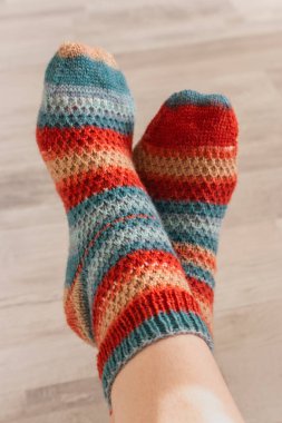 Kadın ayağına renkli örülmüş çoraplar. Çizgili parlak yün çoraplar. Sonbahar için kalın kıyafetler. Samimi örgü moda. El yapımı kıyafetler. Örgü deseni konsepti. 