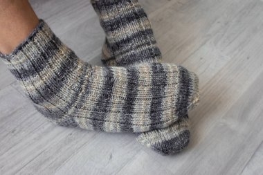 Çizgili çoraplı erkek bacakları. Çapraz bacaklı yün çoraplar. Sonbahar sıcak giysileri. Çoraplar için çizgili örgü deseni. El yapımı moda. Rahat bir yaşam tarzı..