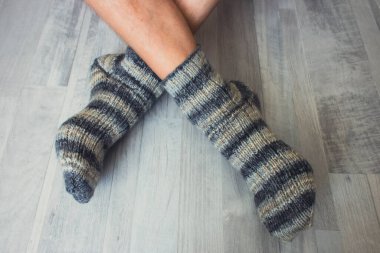 Çizgili çoraplı erkek bacakları. Çapraz bacaklı yün çoraplar. Sonbahar sıcak giysileri. Çoraplar için çizgili örgü deseni. El yapımı moda. Rahat bir yaşam tarzı..