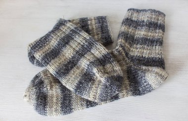 Beyaz arka planda çizgili örgü çoraplar. Gri yün çoraplar. Örgü örerek kapatın. Örgü hobisi. Örgü giyme konsepti. İğne işi arkaplanı. 