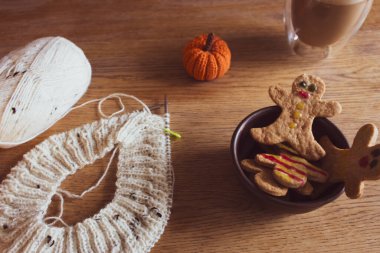 Kahve fincanlı zencefilli kurabiye ve yuvarlak iğneli beyaz tüvit örgü. Süslü kurabiye, gülümseme ve yün iplikle örülmüş balkabağı. Beyaz örgülü ev yapımı bisküviler.. 