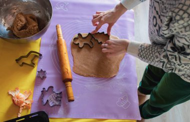 Noel süveterli bir kadın Noel şekilli kurabiyeler yapıyor. Masada merdane, zencefilli ekmek ve mandalina var. Noel arifesi, en güzel manzara. Hamur işi hazırlığı. Ev yapımı tatlı..