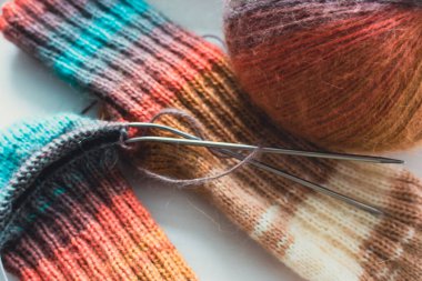 Gökkuşağı renginde örülmüş çoraplar. Örgü moda. Ilık yün çoraplar ve örgü iğneleri. Kıyafetlerin renkleri farklı. Örgü hobileri. El yapımı ürünler. El yapımı örgü giysiler. Parlak örülmüş çoraplar ve iplik yumağı. 