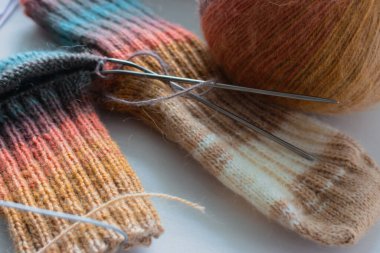 Gökkuşağı renginde örülmüş çoraplar. Örgü moda. Ilık yün çoraplar ve örgü iğneleri. Kıyafetlerin renkleri farklı. Örgü hobileri. El yapımı ürünler. El yapımı örgü giysiler. Parlak örülmüş çoraplar ve iplik yumağı. 