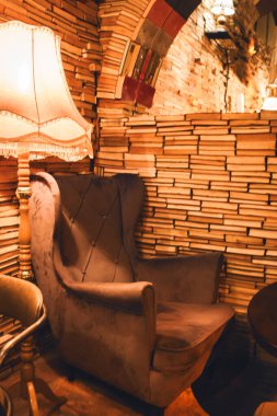 Antika kitapçısında sıcak ışık ve rahat koltuklu Retro Lamba. Antika lambalı ve klasik koltuklu eski kitap yığını. İyi akşamlar. Kütüphanenin içi sıcacık. Edebiyat konsepti. Kitap kulübü tasarımı. Bilgi ve bilgelik. 