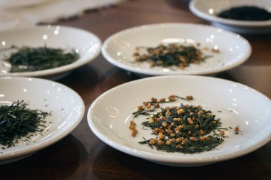 Beyaz tabakta kurumuş yeşil çay yaprakları. Japon kuru çay tatma töreni. Bir yığın Sencha çayı. Sağlıklı yaşam tarzı kavramı. Asya çay kültürü.