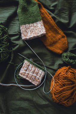 Koyu yeşil iplik yumağı, örgü çorap ve örgü iğneleri. Koyu yeşil arka planı olan yün iplikler. Örgü örerek kapatın. Örgü hobisi. Örgü giyme konsepti. İğne işi arkaplanı. 