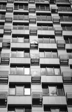 Gökdelen, tek renkli. Kopya alanı olan yüksek katlı bir bina. Modern mimari, siyah ve beyaz. İş yeri binası. Mimaride geometrik çizgiler. Modern kazıyıcı dış görünüş.