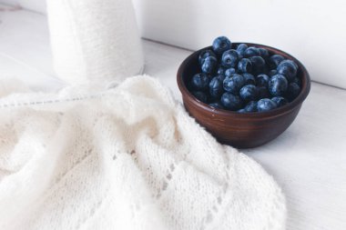 Kil kasesinde taze yaban mersini ve beyaz örgü. Örgü desenli ve pamuklu hırka. Yaz meyveleri ve pamuk örülmüş süveter. Yaz hala hayattır. Organik yiyecekler ve örgü hobisi. 