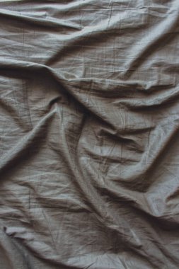 Grey fabric texture. Wavy bed sheet with copy space. Monochrome background. Bedding concept. Green blanket top view. Satin bed sheet. Cotton curve blanket. Abstract background.