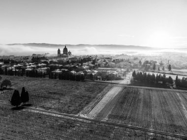 Aerial view of Santa Maria degli Angeli town and church at sunset, with meadows covered by snow.