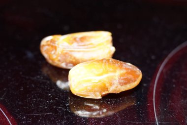 Sıcak renkli bir avuç dolusu hurma doğal bir yüzeye nazikçe uzanır. Derin parıltılarını ve buruşuk dokularını ortaya çıkarır. Parlak ciltleri, doğal şeker bakımından zengin, karşı konulmaz bir tatlılığı çağrıştırıyor.. 