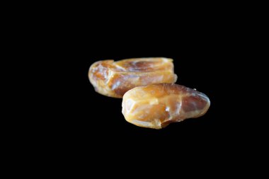 Sıcak renkli bir avuç dolusu hurma doğal bir yüzeye nazikçe uzanır. Derin parıltılarını ve buruşuk dokularını ortaya çıkarır. Parlak ciltleri, doğal şeker bakımından zengin, karşı konulmaz bir tatlılığı çağrıştırıyor.. 