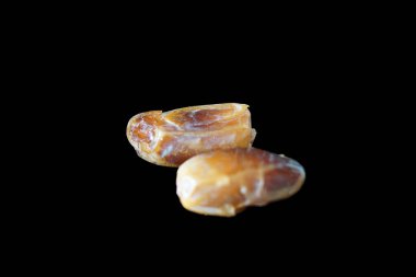 Sıcak renkli bir avuç dolusu hurma doğal bir yüzeye nazikçe uzanır. Derin parıltılarını ve buruşuk dokularını ortaya çıkarır. Parlak ciltleri, doğal şeker bakımından zengin, karşı konulmaz bir tatlılığı çağrıştırıyor.. 