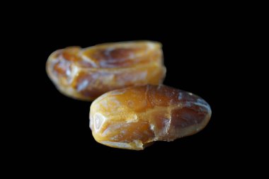 Sıcak renkli bir avuç dolusu hurma doğal bir yüzeye nazikçe uzanır. Derin parıltılarını ve buruşuk dokularını ortaya çıkarır. Parlak ciltleri, doğal şeker bakımından zengin, karşı konulmaz bir tatlılığı çağrıştırıyor.. 