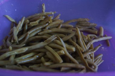 Bir avuç taze yeşil fasulye, taze ve canlı, doğal ışıkta yakalanmış. İnce şekilleri ve canlı renkleri bahçenin tazeliğini ve sağlıklı, lezzetli yemeklerin basitliğini çağrıştırıyor..