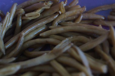 Bir avuç taze yeşil fasulye, taze ve canlı, doğal ışıkta yakalanmış. İnce şekilleri ve canlı renkleri bahçenin tazeliğini ve sağlıklı, lezzetli yemeklerin basitliğini çağrıştırıyor..