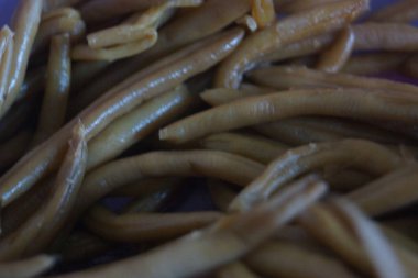 Bir avuç taze yeşil fasulye, taze ve canlı, doğal ışıkta yakalanmış. İnce şekilleri ve canlı renkleri bahçenin tazeliğini ve sağlıklı, lezzetli yemeklerin basitliğini çağrıştırıyor..