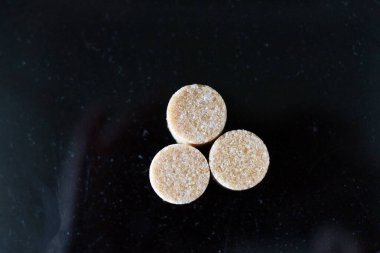 Kahverengi şeker küpleri ışığın altında pırıl pırıl parıldıyor ve mükemmel kübik şekillerini ve narin kristallerini ortaya çıkarıyor. Hafif kumlu dokuları kusursuz parlaklıklarına zıt düşerken ışık yüzeylerinde ince yansımalar yaratıyor.. 