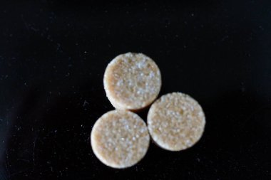 Kahverengi şeker küpleri ışığın altında pırıl pırıl parıldıyor ve mükemmel kübik şekillerini ve narin kristallerini ortaya çıkarıyor. Hafif kumlu dokuları kusursuz parlaklıklarına zıt düşerken ışık yüzeylerinde ince yansımalar yaratıyor.. 