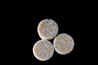 Kahverengi şeker küpleri ışığın altında pırıl pırıl parıldıyor ve mükemmel kübik şekillerini ve narin kristallerini ortaya çıkarıyor. Hafif kumlu dokuları kusursuz parlaklıklarına zıt düşerken ışık yüzeylerinde ince yansımalar yaratıyor.. 