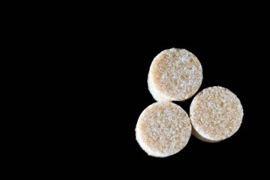 Kahverengi şeker küpleri ışığın altında pırıl pırıl parıldıyor ve mükemmel kübik şekillerini ve narin kristallerini ortaya çıkarıyor. Hafif kumlu dokuları kusursuz parlaklıklarına zıt düşerken ışık yüzeylerinde ince yansımalar yaratıyor.. 