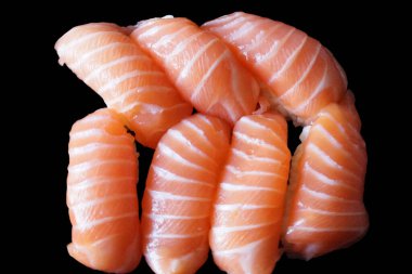 Çok güzel düzenlenmiş somon suşisi, yeni hazırlanmış ve ince bir tabağa güzelce yerleştirilmiş. Somon dilimleri ışığın altında parıldıyor, yumuşak dokularını ve canlı renklerini sergiliyorlar..