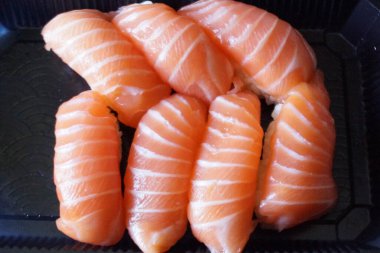 Çok güzel düzenlenmiş somon suşisi, yeni hazırlanmış ve ince bir tabağa güzelce yerleştirilmiş. Somon dilimleri ışığın altında parıldıyor, yumuşak dokularını ve canlı renklerini sergiliyorlar..