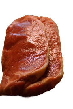 A generous cut of ribeye steak, beautifully marbled, rests on a rustic wooden board. The tender fibers and deep color of the meat highlight the richness of this premium cut, poised to deliver full flavor.