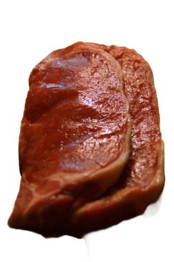 A generous cut of ribeye steak, beautifully marbled, rests on a rustic wooden board. The tender fibers and deep color of the meat highlight the richness of this premium cut, poised to deliver full flavor.