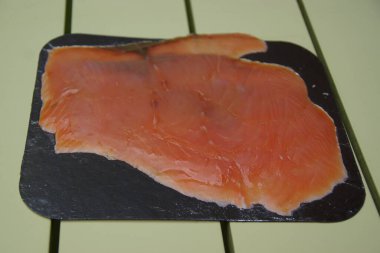 Yumuşak dalgalanmalarla doğal zarafetlerini arttıran yumuşak bir tabağa tütsülenmiş somon dilimleri. Somonların turuncu-pembe tonu ve ipeksi şeffaflığı hem ince hem de zengin tadını ortaya çıkarır.. 