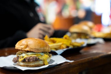 Eritilmiş peynirli bir çizburger ve patates kızartmasıyla servis edilen turşu. 