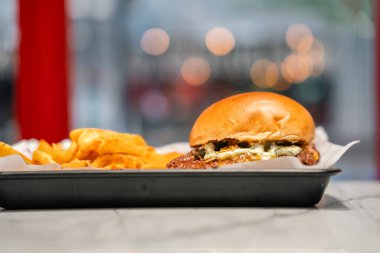 Tepside patates kızartmasıyla servis edilen lezzetli bir hamburger. Arka tarafta.