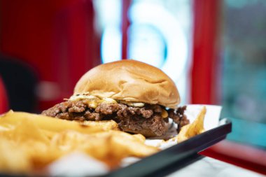 Tepside patates kızartmasıyla servis edilen lezzetli bir hamburger. Arka tarafta.