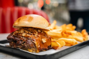 Tepside patates kızartmasıyla servis edilen lezzetli bir hamburger. Arka tarafta.