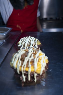 Aşçı çeşnili taze hazırlanmış erimiş peynirli ve soslu hamburgerler..