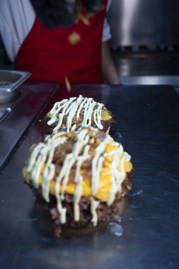 Aşçı çeşnili taze hazırlanmış erimiş peynirli ve soslu hamburgerler..