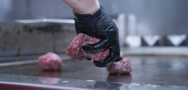 Şef hamburgerler için ızgaraya kıyma koyuyor..