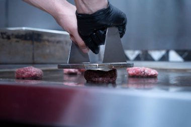 Şef ızgarada hamburger köftesi eziyor..
