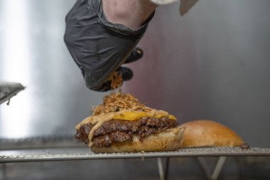 Şef, Mutfakta Erimiş Çedar ve Çıtır Soğanlı Ezilmiş Burger Hazırlıyor