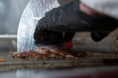 Şefin Yakın Çekimi Sulu Smash Burger Patty Metal Spatula ile kızgın ızgarada