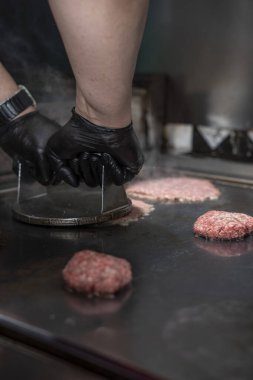 Şef ızgaraya çiğ hamburger köftesi sıkıştırıyor. Burger tuşuna bas