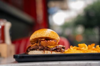 Patates kızartmasıyla servis edilen soğan halkaları ve barbekü soslu gurme Smash Burger.