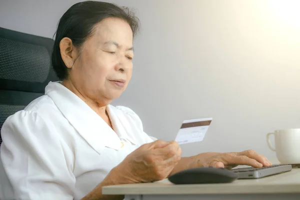 stock image Asian elderly woman typing in credit card number for online shopping to purchase goods or services online through the internet