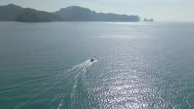 Bir İHA 'nın, turkuaz mavi denizde gün ortasında hızla giden bir gemiyi görüntülediği bir video.