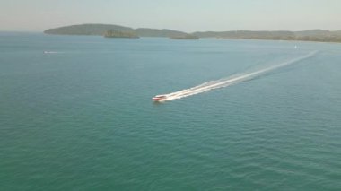 Bir İHA 'nın, turkuaz mavi denizde gün ortasında hızla giden bir gemiyi görüntülediği bir video.