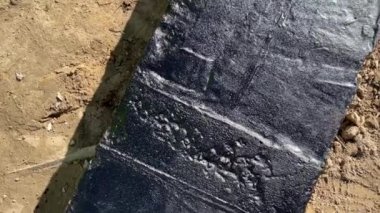 Beton temeli 4k ağır çekimde uygulanan ziftöz astar dokusunun üst görünümü. Temel su geçirmez inşaat çalışmaları